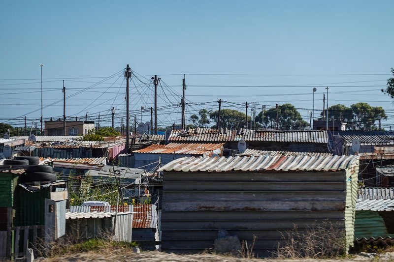 Aerial perspective of corrugated iron roofs in an urban informal settlement under a clear sky.