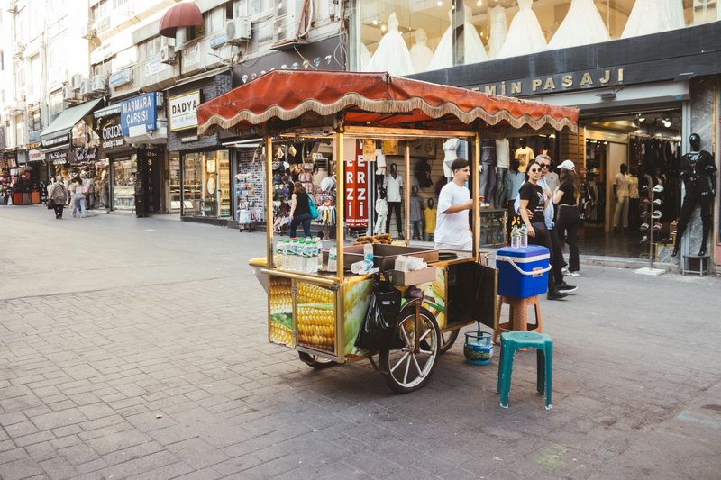 Street vendor cart selling beverages in a lively urban shopping street.