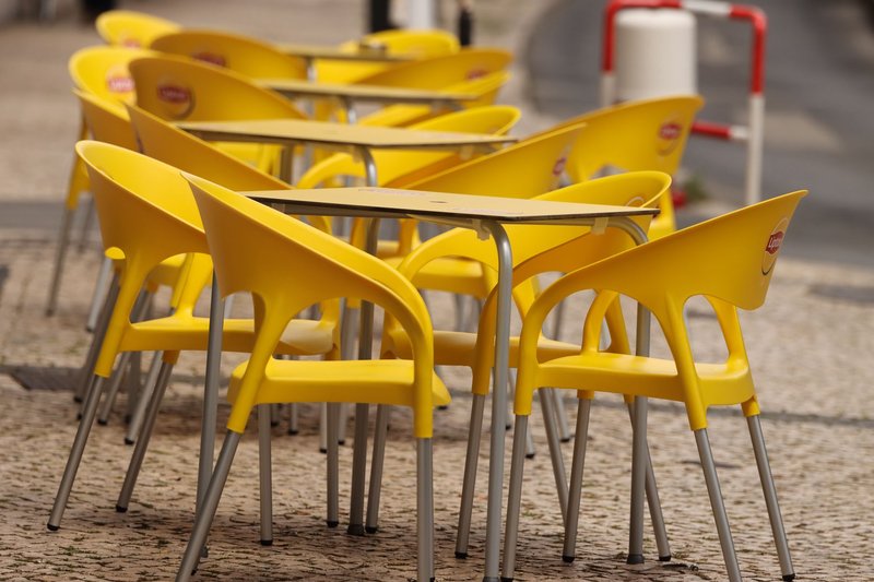 Vibrant yellow chairs and tables on a cobblestone street in Lisbon, Portugal.