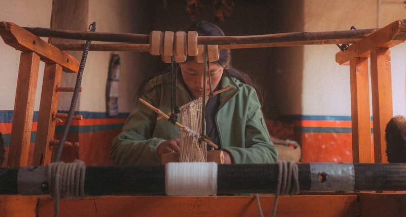 A woman focused on weaving with a traditional loom, showcasing cultural craftsmanship.