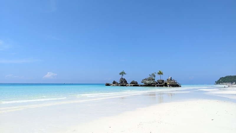 Scenic view of a pristine white sand beach and turquoise water under a clear blue sky.