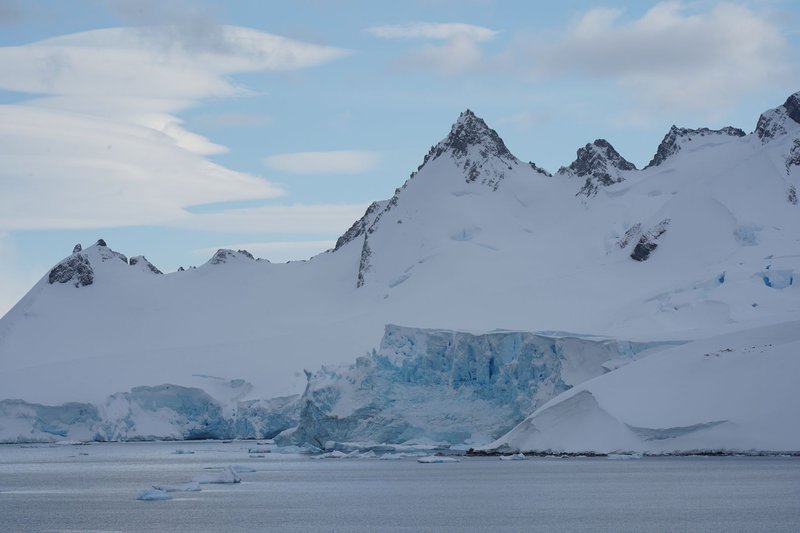 Stunning view of Antarctic glacier with rugged mountain peaks under a clear blue sky.