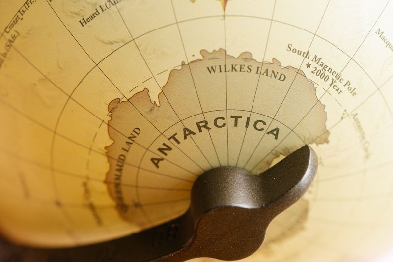Close-up of a vintage globe highlighting Antarctica with detailed geographic labels.