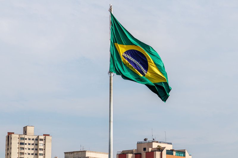 Brazilian flag waving against São Paulo skyline, showcasing patriotism and urban architecture.