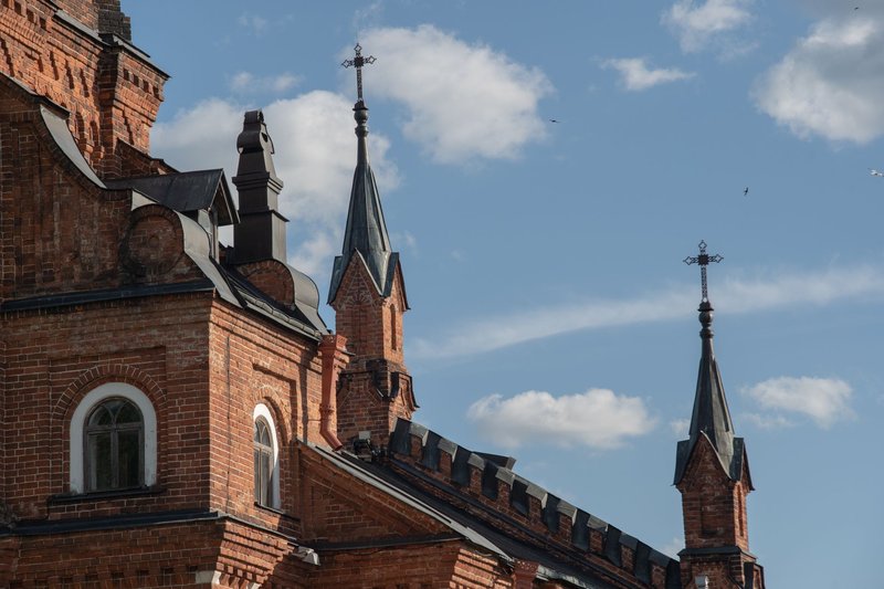 Gothic-style red brick church exterior with intricate spires against a blue sky.