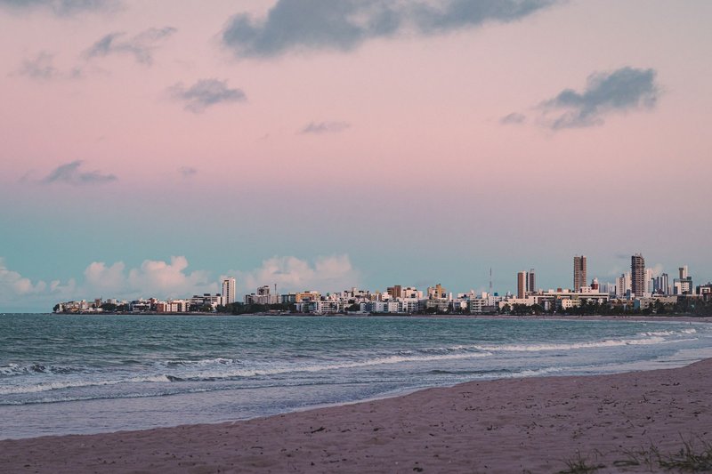 A serene city skyline along the coast during twilight with warm pink hues.