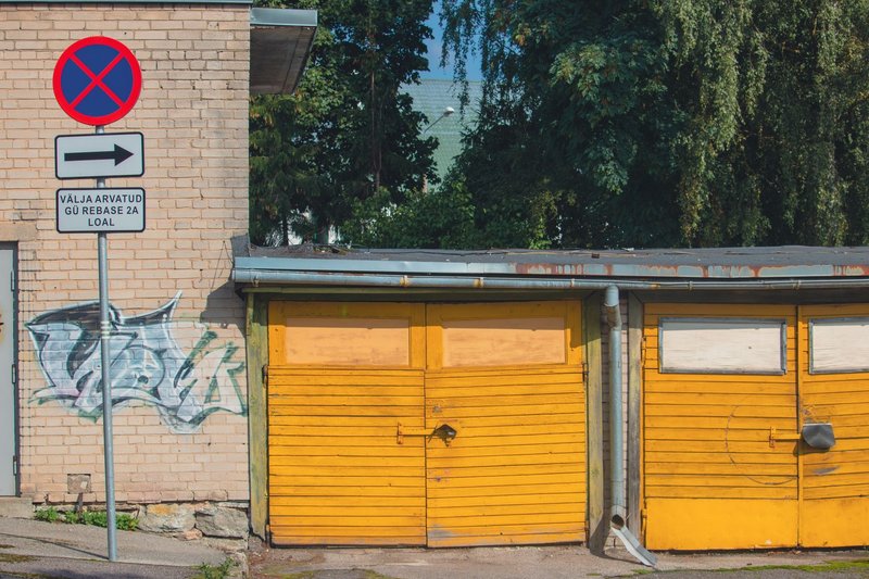 Yellow garage doors and graffiti on a brick wall in Tartu, Estonia, with vibrant urban elements.