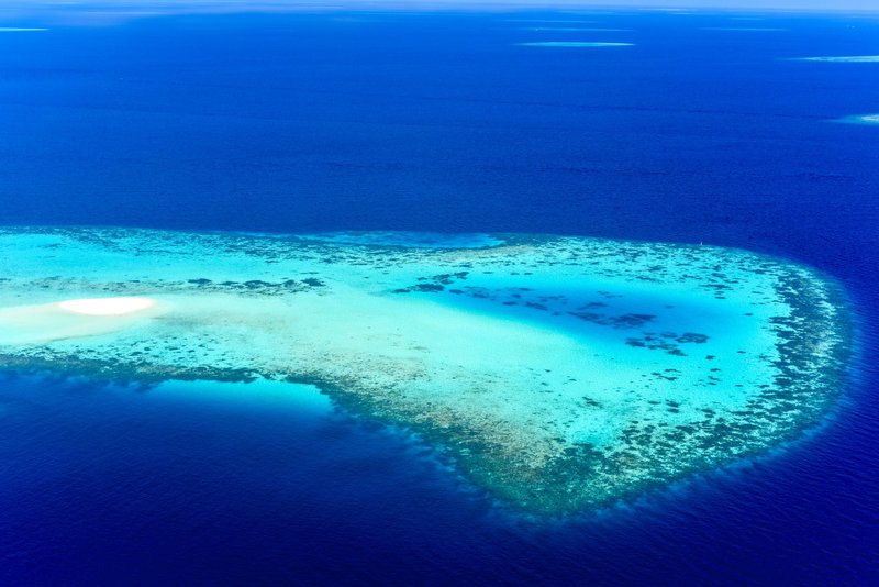 Stunning aerial view of vibrant coral reefs and turquoise waters in Eydhafushi, Maldives.