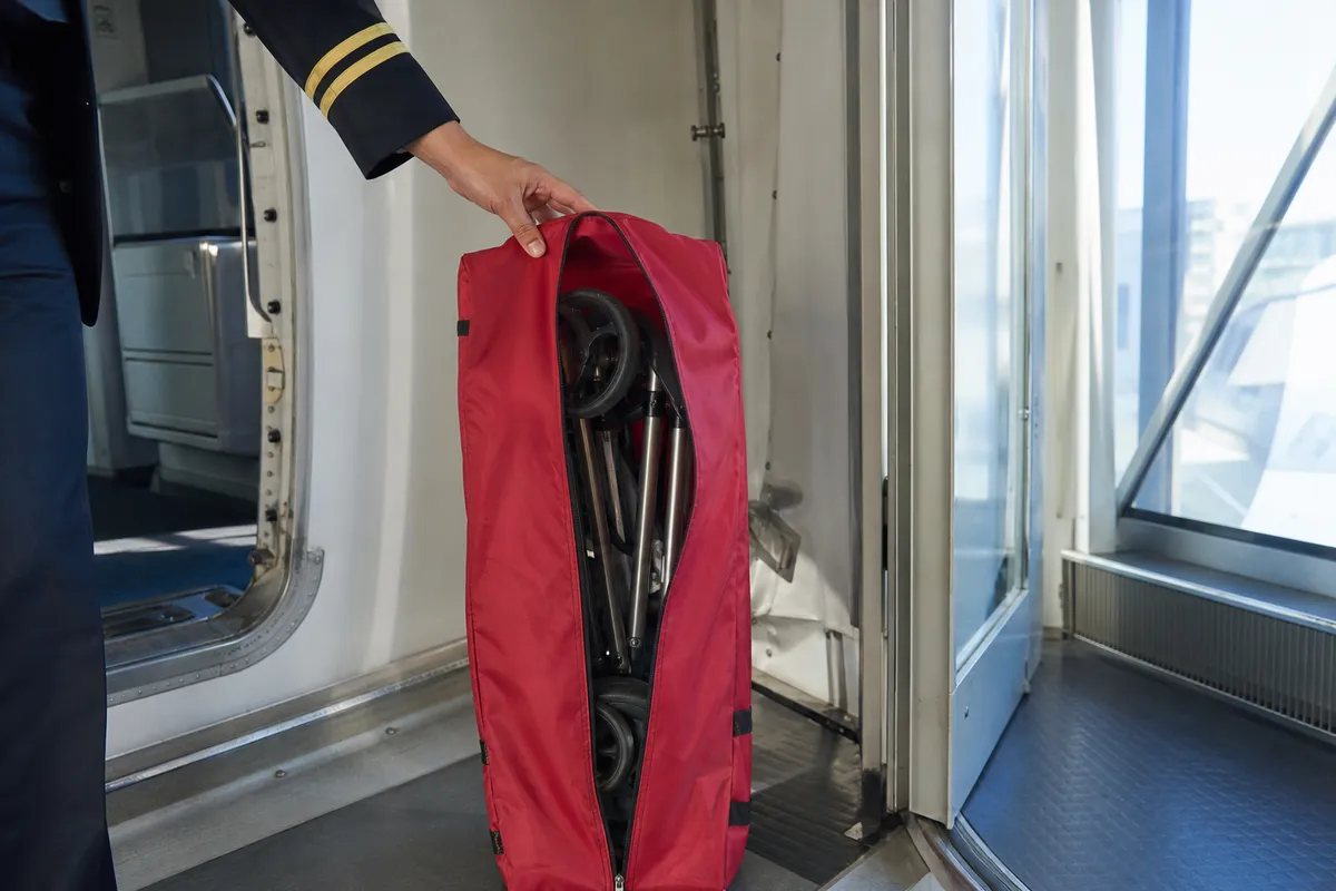 Umbrella stroller in a red padded gate-check bag at the aircraft door