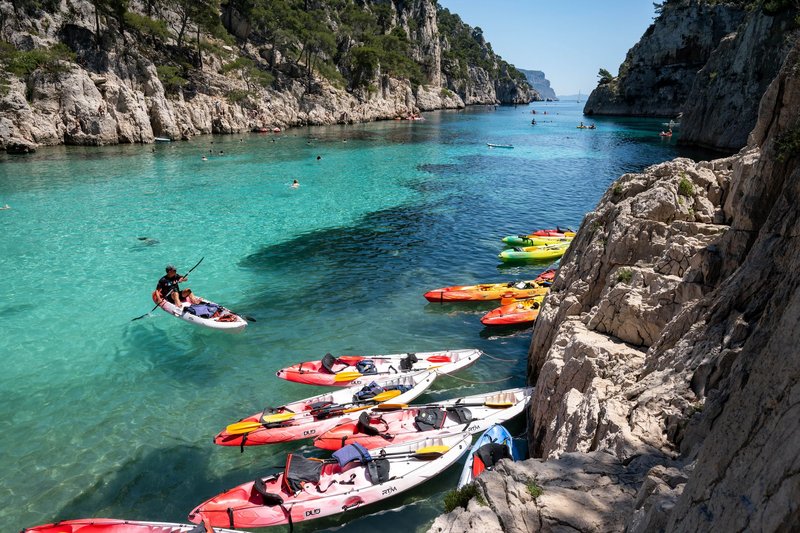 Kayakers exploring the turquoise waters of Calanques National Park in France on a sunny day.