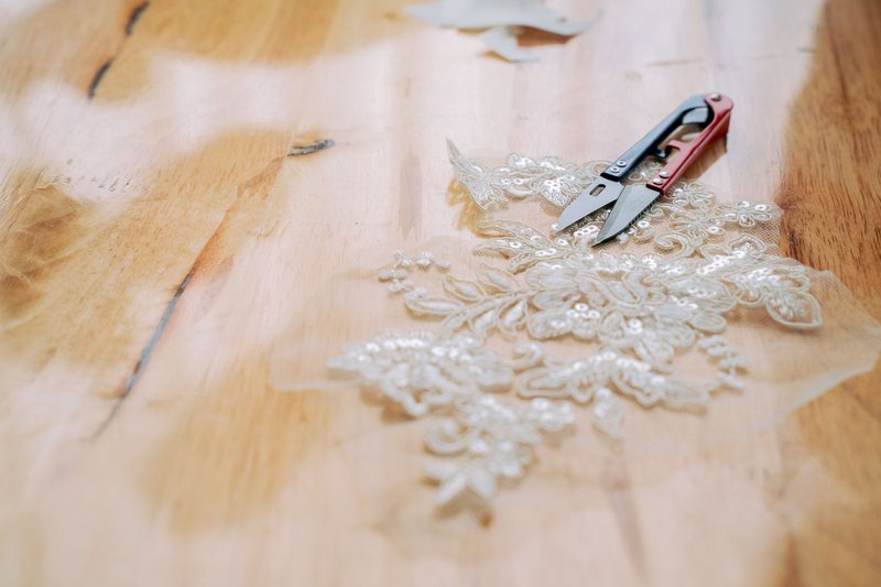 Lace and scissors on a wooden table, perfect for craft and sewing themes.