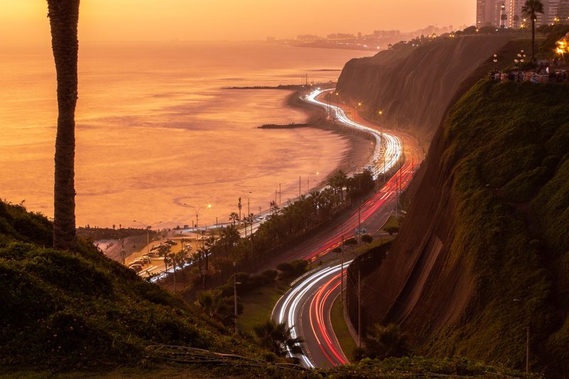 Beautiful sunset view of Lima coastline with light trails of cars along the Pacific Ocean.