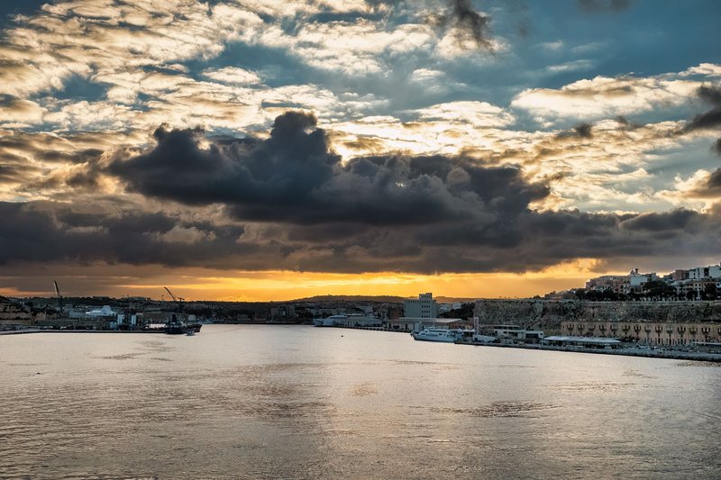 Breathtaking sunset view over Valletta harbor in Malta with vibrant clouds and tranquil water.