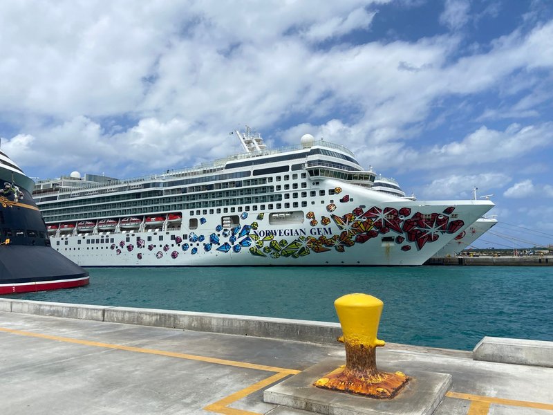 Vibrant Norwegian Gem cruise ship docked at Nassau port under a bright blue sky.