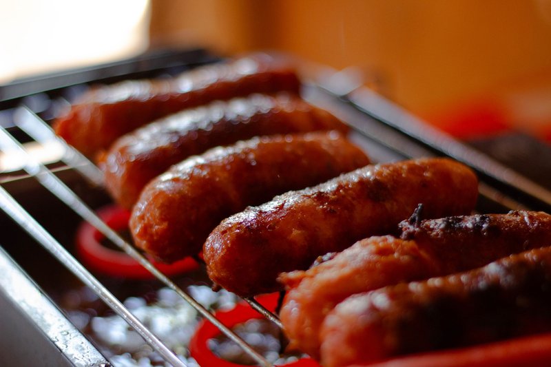 Succulent sausages sizzling on a grill, captured in warm, mouth-watering detail.