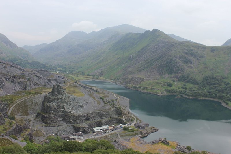 A stunning aerial view of Snowdonia's rugged landscape featuring mountains, valleys, and a serene lake.