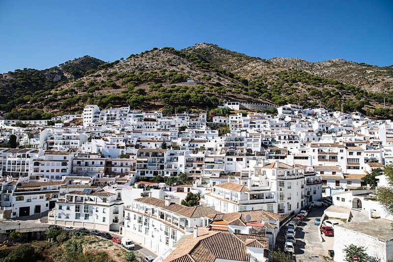 Charming view of a whitewashed Spanish town nestled in the hills during a sunny day.