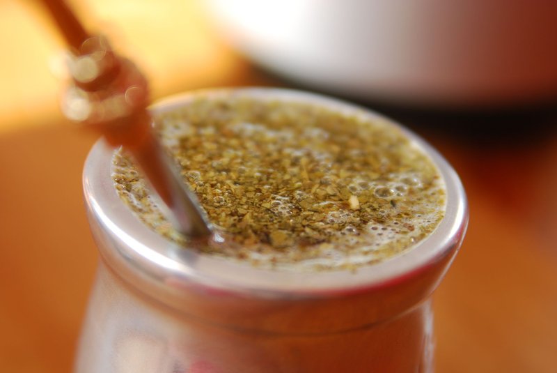 A detailed view of a traditional yerba mate drink with a straw in a metal cup.