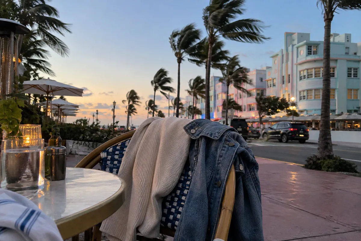 Knit sweater and denim jacket on an outdoor cafe chair on a windy January evening in South Beach